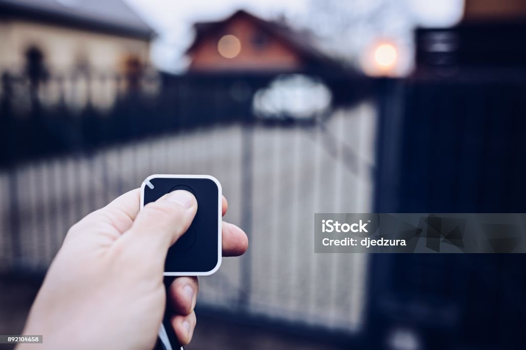 Man opening automatic property gate Man opening automatic property gate with remote controller Gate Stock Photo