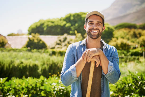 My farm is my life Portrait of a happy young farmer holding a spade while posing in the fields on his farm gardening stock pictures, royalty-free photos & images