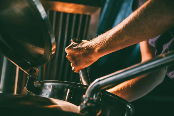 trabajador de sexo masculino operar maquinaria en fábrica de cerveza - destilería fotografías e imágenes de stock