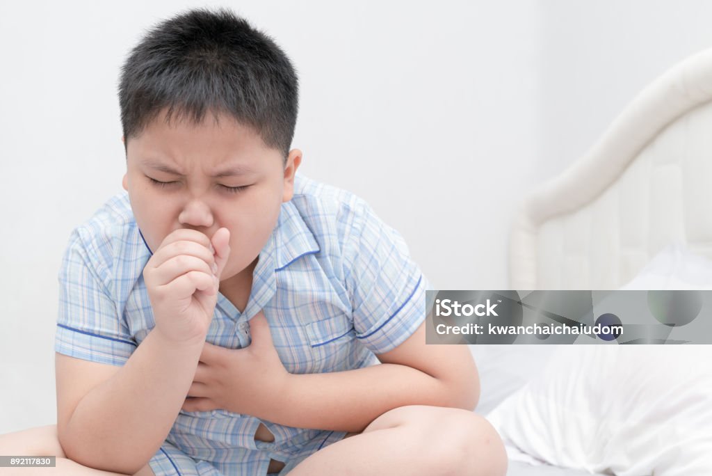 Sick obese boy is coughing and throat infection Sick obese boy is coughing and throat infection on bed, health care concept Child Stock Photo