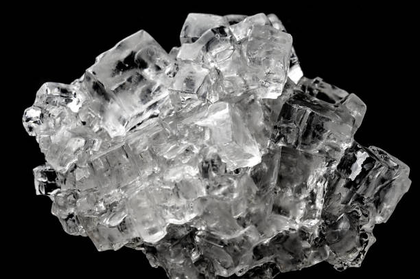kubische salzkristall aggregat auf schwarzem hintergrund - salz mineral stock-fotos und bilder