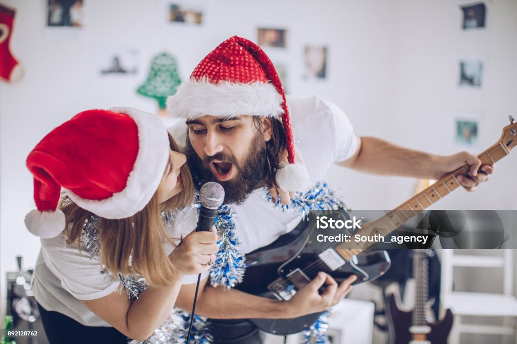 Christmas celebration together Two people, young heterosexual couple, man playing guitar and singing, in home studio on christmas day.
 Christmas Stock Photo
