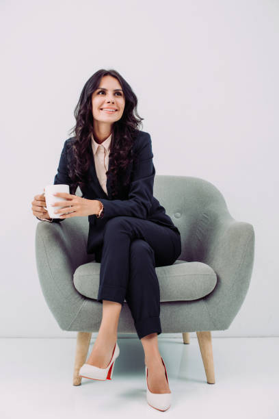 businesswoman with cup of hot drink - sitting on a chair imagens e fotografias de stock