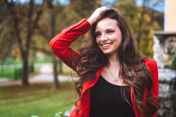 istock Young girl in red jacket playing with her hair 892148180