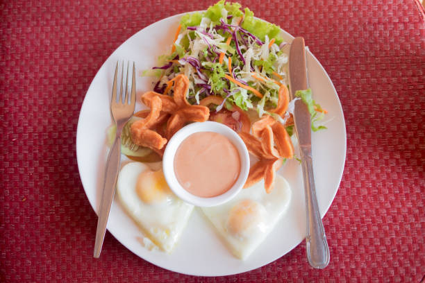 Homemade breakfast with vegetable salad, hotdog and fried egg