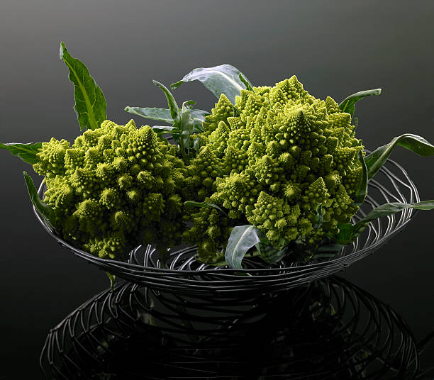 romanesco cauliflower in basket two romanesco cauliflower in metal basket, dark reflective back vermehrung stock pictures, royalty-free photos & images