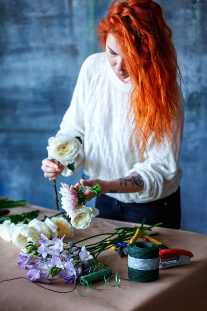 istock Charming cheerful female shop assistant making bouquet with purple crocus, Eucalyptus poplaraceous populus and Chrysanthemum single-headed Anastasia white 892258424