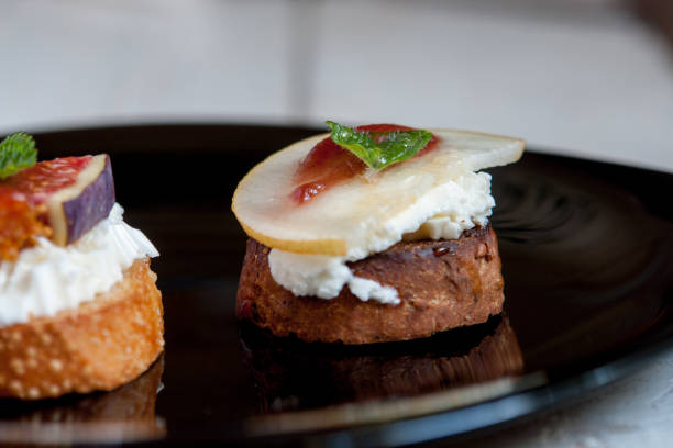 istock Bruschetta with goat cheese, pear and figs on black plate 892258426