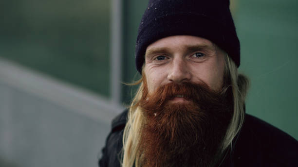 istock drunk homeless sleepy man smiling and looking at the camera while sitting on bench at the sidewalk 892294234