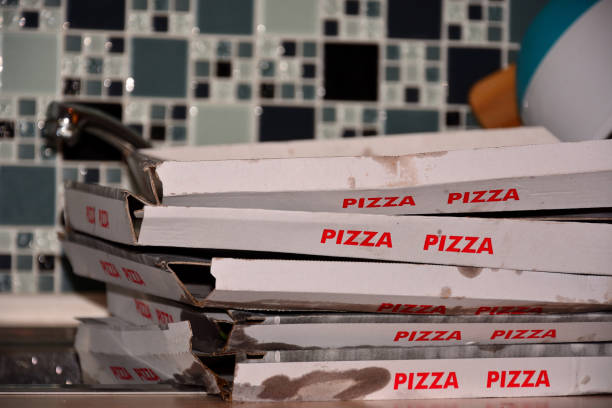 Five empty dirty boxes of pizza lie on the kitchen table. stock photo