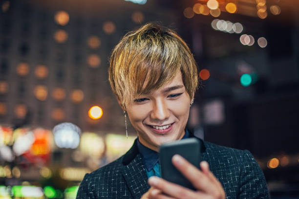 istock Young Japanese man with smart phone at night 892333696