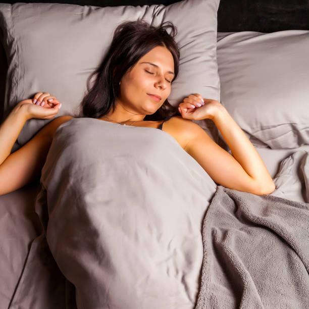 istock Woman sleeping in bed and stretch oneself on a dark background. 892338332