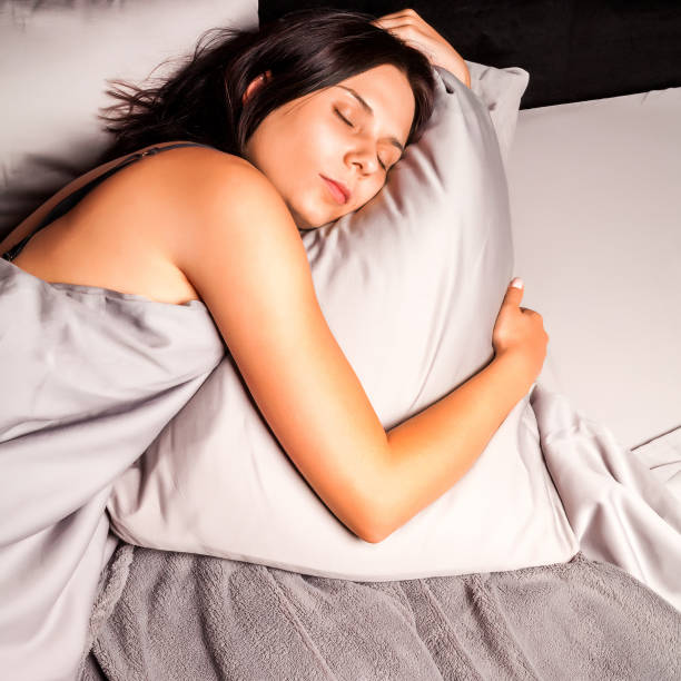 istock Woman sleeping in bed on a dark background. 892338570