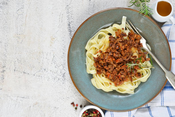 istock Sauce Bolognese with tagliatelle and Parmesan cheese on a concrete background. 892345742