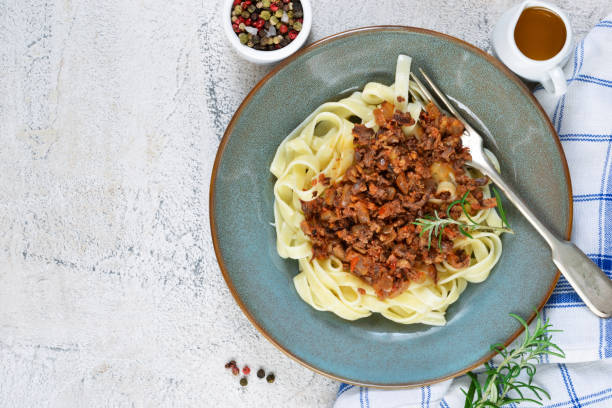 istock Sauce Bolognese with tagliatelle and Parmesan cheese on a concrete background. 892345764
