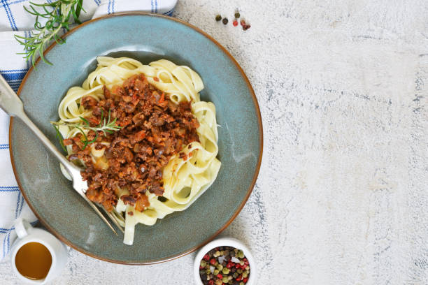 istock Sauce Bolognese with tagliatelle and Parmesan cheese on a concrete background. 892345770