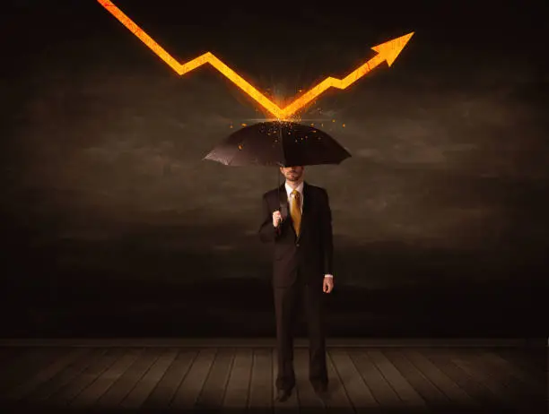 Photo of Businessman standing with umbrella keeping orange arrow