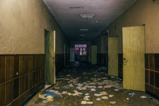 istock Dark scary corridor with opened doors in abandoned ruined clinic, perspective 892346154