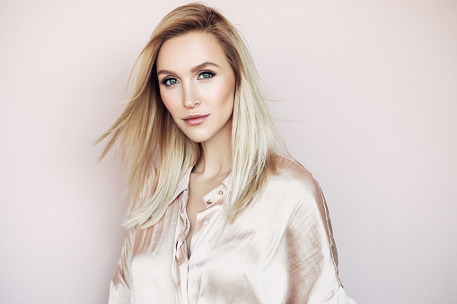 Portrait of beautiful looking young blonde woman with the middle length hair, wearing in a delicate makeup.Perfect model straightly gazing  at the viewer with toothy smile. Beauty, elegance, hairstyling and cosmetics.