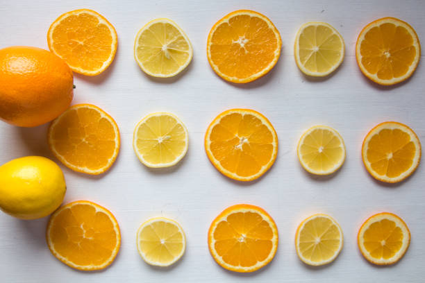 Cut lemons and oranges on white wood background