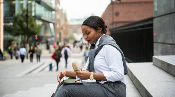 istock Businesswoman eating  sandwich and using smart phone 892382102