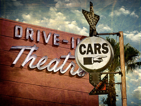 aged and worn drive in theater sign with palm trees