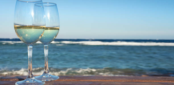 istock Two white wine wineglasses over sea background. 892398574