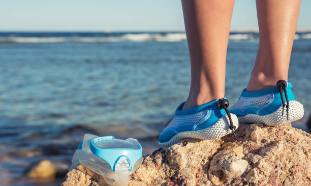 Female feet in aqua shoes near reefs and corals . stock photo