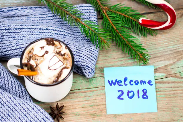 Photo of New Year 2018 concept. Cup of coffee and sticky note on wood table writing Welcome 2018.