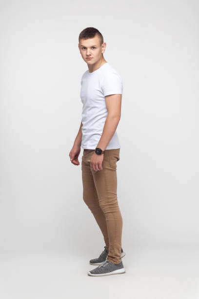 istock Full height young boy standing near gray wall and looking at camera. 892443572