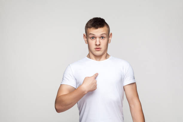 Surprised boy looking at camera and pointing finger himself.