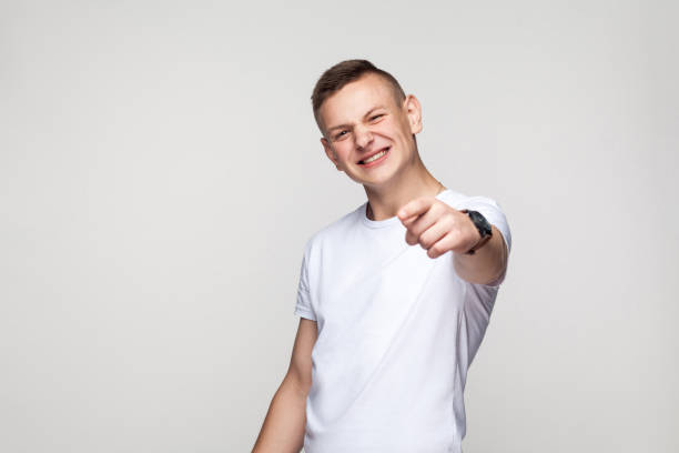 Happiness young boy pointing finger at camera and toothy smiling Happiness young boy pointing finger at camera and toothy smiling. Studio shot big ears stock pictures, royalty-free photos & images