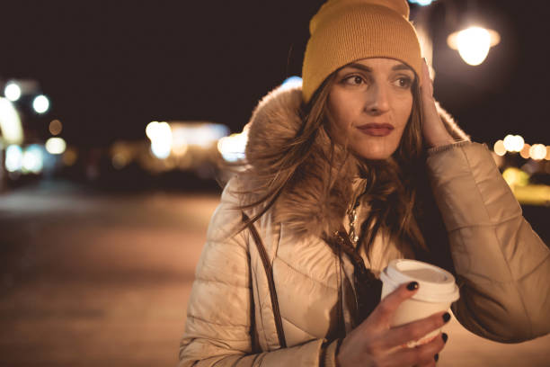 Cute young woman with coffee at night in the city