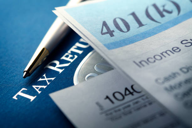 401k Statement And Federal Tax Return A 401k statement rests on top of a U.S. Federal 1040 income tax return and is photographed using a very shallow depth of field. This image conveys the tax implications of saving for and taking distributions from retirement accounts. pension photos stock pictures, royalty-free photos & images