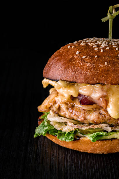 istock Cheese burger with grilled meat, cheese, tomato on dark wooden surface. Ideal for advertisement. Close-up 892460496