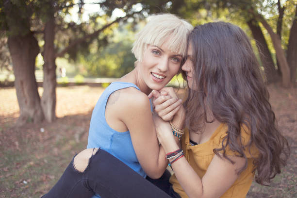 istock Girls sitting in park and embracing 892478210