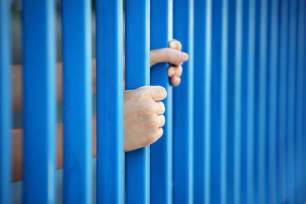 istock hands of prisoner in jail background. 892496466