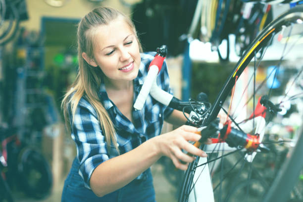 istock Young female is fixing wheels of bicycle in workshop. 892507798