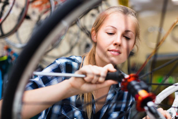 istock Young woman master is repairing bicycle in workshop. 892507820