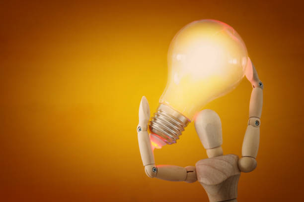 istock Wooden dummy holding shiny light bulb. New idea concept or choosing the right solution. 892507856