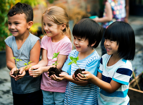Group of diverse kids holding plants