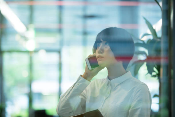 Asian woman are using smartphone in office building  through the window