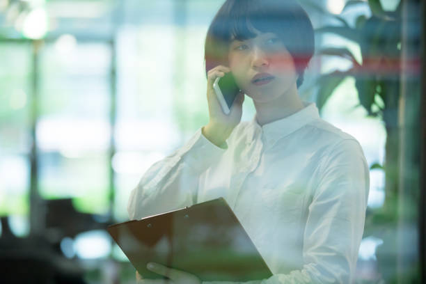 istock Asian woman are using smartphone in office building  through the window 892550776