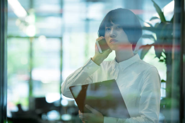 istock Asian woman are using smartphone in office building  through the window 892550788