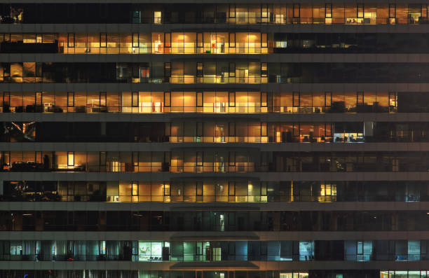 istock office building at night. Late night at work. Glass curtain wall office building 892574150
