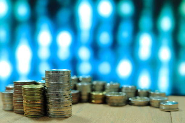 istock vintage digital economy coin pile stacked in to columns on wooden board. digital binary code in the background 892578282