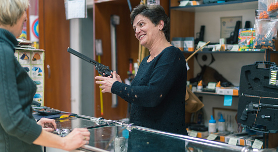 The mature blonde woman buying the revolver in the small gun store