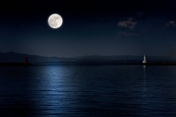 Full moon rising over the sea and the lighthouse Full moon rising over the sea and the lighthouse with copy space. moonlight stock pictures, royalty-free photos & images