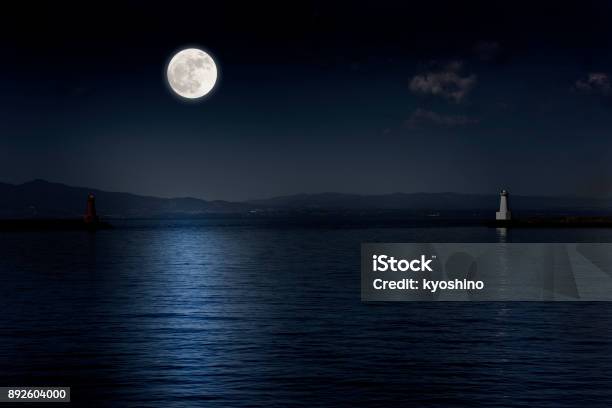 Full Moon Rising Over The Sea And The Lighthouse Stock Photo - Download Image Now - Moon, Sea, Night