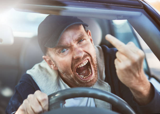 istock Furious male driver shouts and gestures obscenely through car windshield 892611822